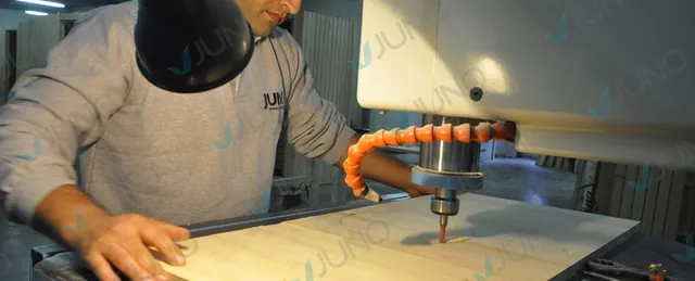 Artisan usinant un panneau de bois sur une fraiseuse à commande numérique